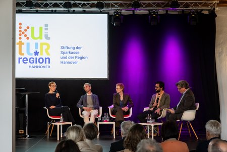 Eine Diskussionsrunde auf der Bühne vor Publikum