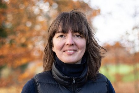 Eine junge Frau blickt lächelnd in die Kamera