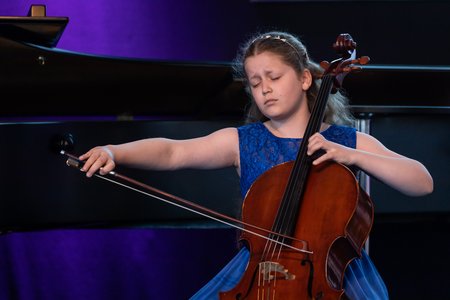 Ein junges Mädchen im blauen Kleid spielt Cello