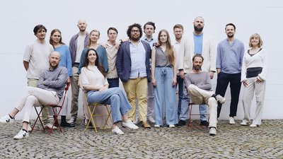Eine Gruppe fröhlicher Menschen steht und sitzt zusammen